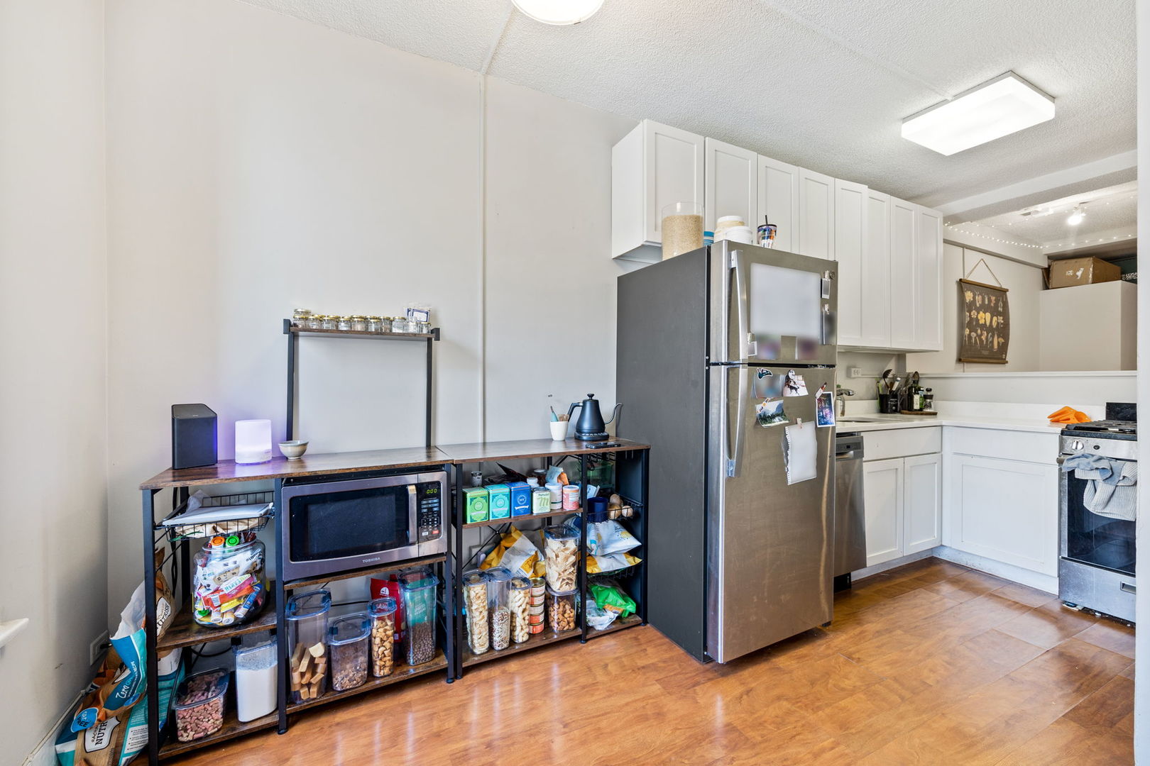 725 West Sheridan Road, Unit 301 Chicago, IL 60613 - Photo 6 of 14 a kitchen with stainless steel appliances a refrigerator and a wooden floor