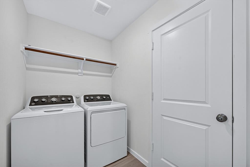 1260 Balsam Road Wilmer, TX 75172 - Photo 8 of 20 Dedicated laundry space featuring a white top-load washer and dryer, an overhead storage shelf with a hanging rod, and light wood-finish flooring