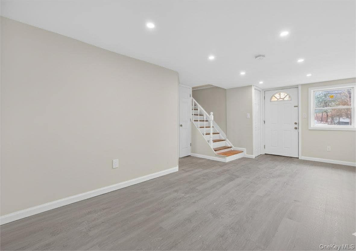 149 Lewis Lane, Unit 3 Wallkill, NY 12589 - Photo 5 of 11 an empty room with wooden floor and stairs