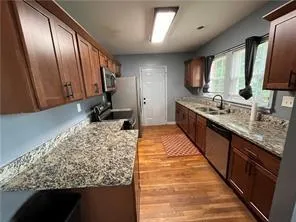 a large kitchen with kitchen island granite countertop wooden cabinets and stainless steel appliances
