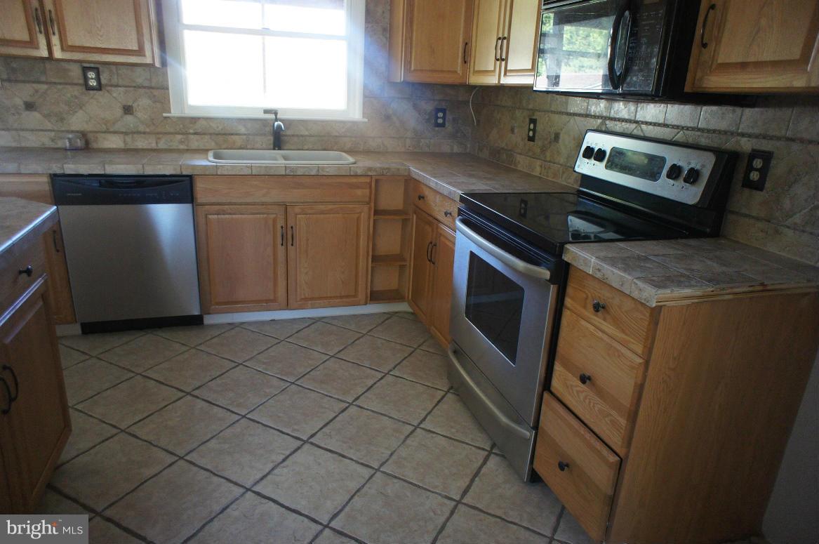 3042 Soper Road Huntingtown, MD 20639 - Photo 12 of 15 a kitchen with stainless steel appliances granite countertop a sink stove and microwave
