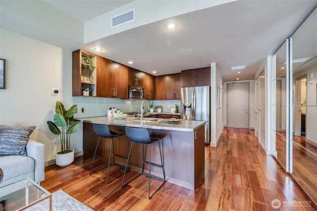 a living room with stainless steel appliances kitchen island granite countertop furniture wooden floor and a view of kitchen