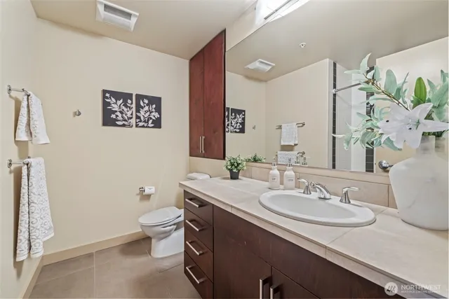 a bathroom with a granite countertop sink a toilet and a mirror
