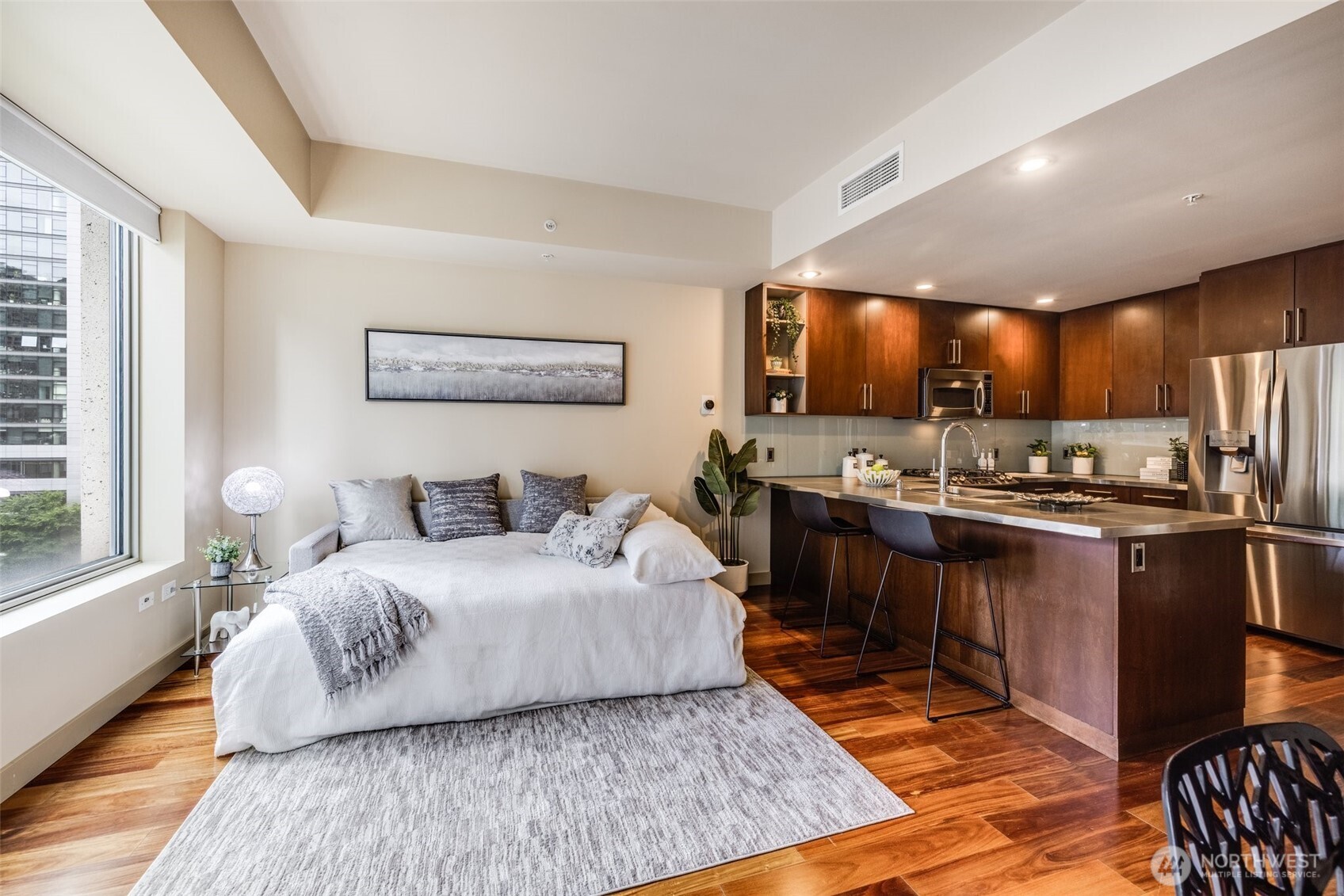 900 Lenora Street, Unit W402 Seattle, WA 98121 - Photo 8 of 39 a spacious bedroom with a bed a dresser and wooden floor
