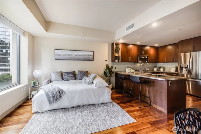 a spacious bedroom with a bed a dresser and wooden floor