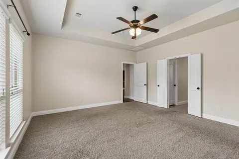 an empty room with chandelier fan and windows