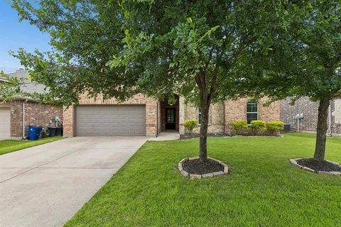 a front view of a house with a yard and tree