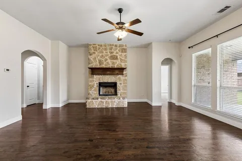 an empty room with wooden floor a fireplace and windows