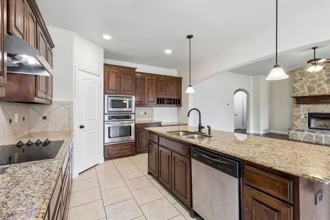a kitchen with stainless steel appliances granite countertop a sink a stove and a wooden cabinets