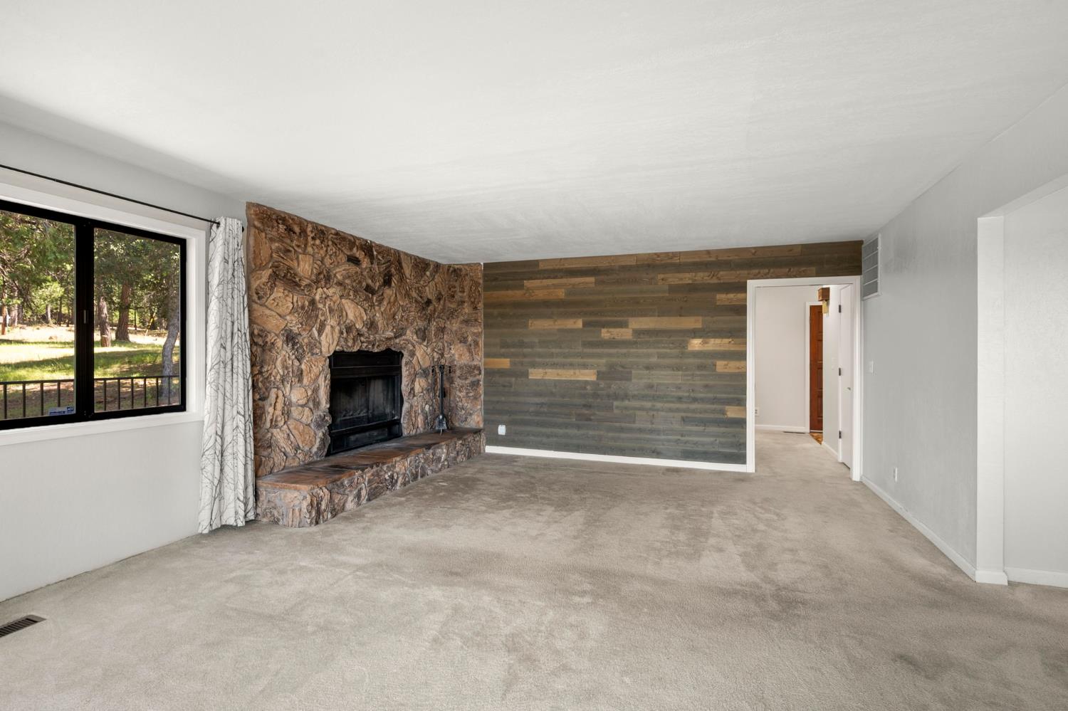 24835 Shake Ridge Road Volcano, CA 95689 - Photo 15 of 79 a view of an empty room with a fireplace and a window
