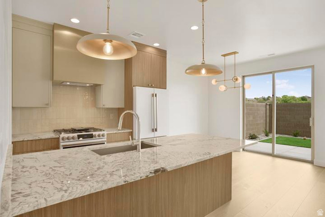 990 Manen Street Washington, UT 84780 - Photo 4 of 43 Contemporary kitchen featuring a large island with an undermount sink, stainless steel appliances, a gas range, and wood-finish flooring