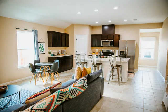 a living room with stainless steel appliances furniture and a kitchen view