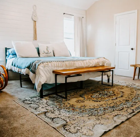 a bed sitting in a bedroom next to a window with a rug
