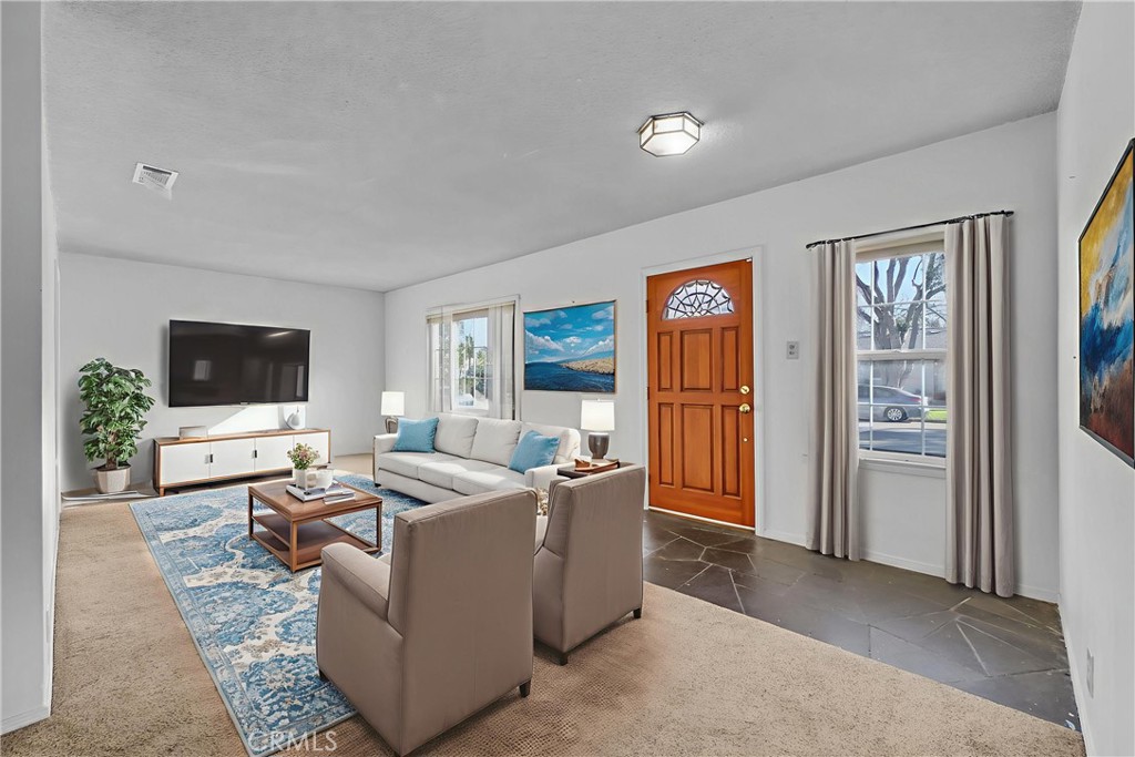 a living room with furniture a flat screen tv and a refrigerator