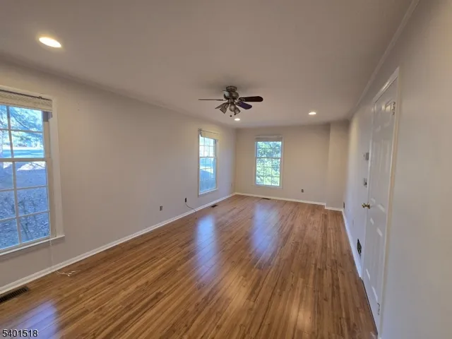 a view of an empty room with a window and wooden floor