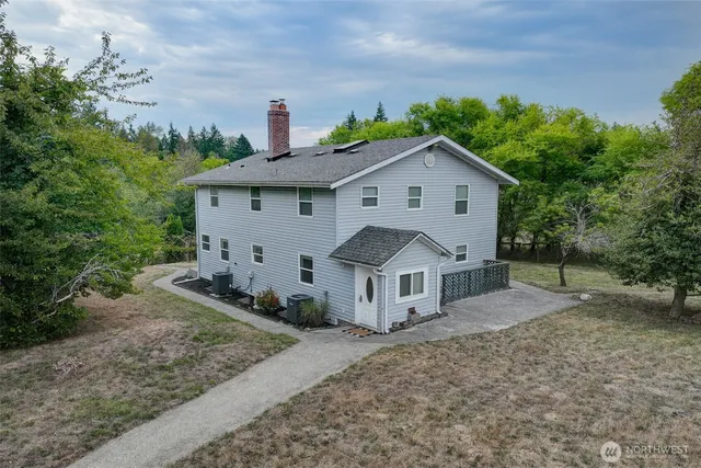 a view of a house with a yard and large trees
