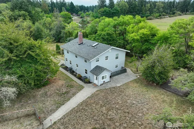 an aerial view of a house with yard and trees in the background