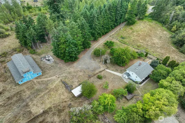 an aerial view of a house with a yard and trees all around
