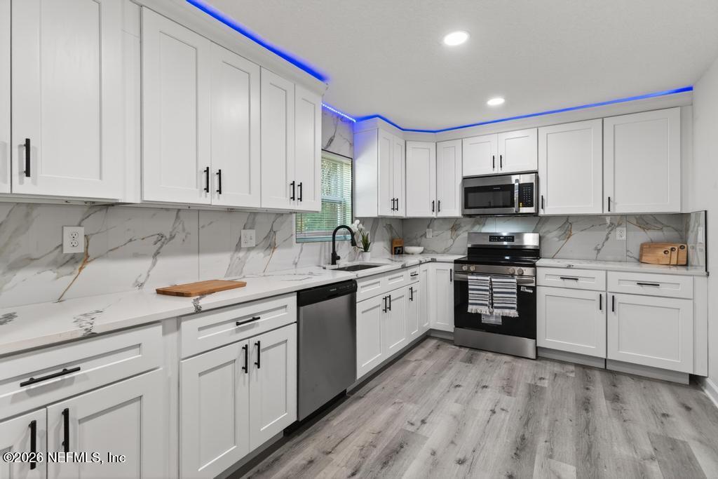 433 Lena Street St. Augustine, FL 32084 - Photo 7 of 42 a kitchen with kitchen island granite countertop white cabinets white stainless steel appliances with a sink and dishwasher