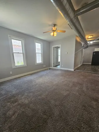 an empty room with windows and ceiling fan