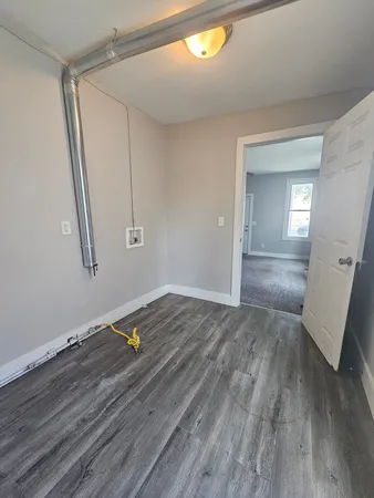 an empty room with wooden floor and mirror