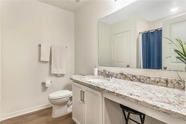 a bathroom with a granite countertop sink a toilet and mirror