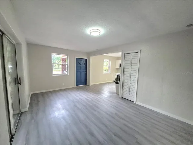 an empty room with wooden floor and windows