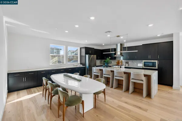 a kitchen with stainless steel appliances kitchen island granite countertop a table chairs sink and cabinets