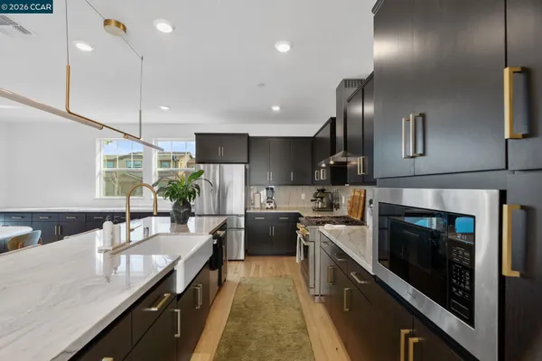a kitchen with kitchen island granite countertop lots of counter top space a sink stainless steel appliances and cabinets