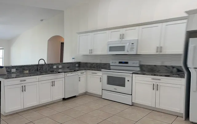 a kitchen with granite countertop white cabinets and white appliances