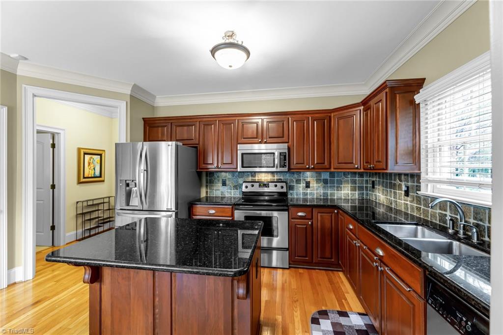 5909 Ballinger Road, Unit A Greensboro, NC 27410 - Photo 12 of 41 Kitchen features include tile back splash, island , granite counter tops, tile backsplash, and under cabinet lighting