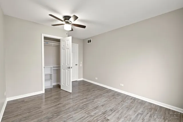 an empty room with wooden floor ceiling fan and windows