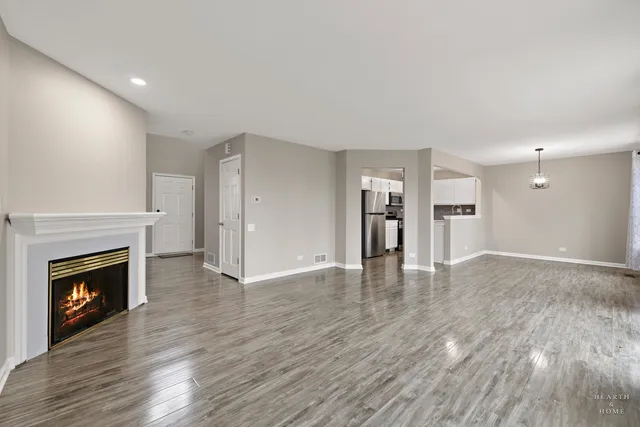a view of an empty room with wooden floor fireplace and a window