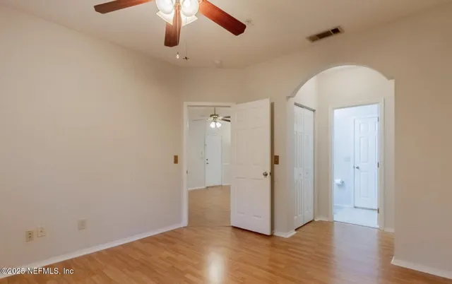 an empty room with wooden floor fan and windows