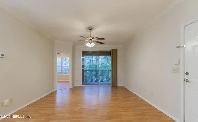 an empty room with wooden floor and fan