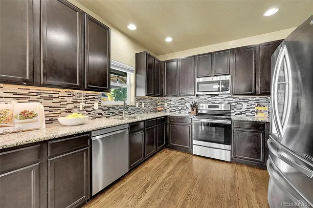 a kitchen with stainless steel appliances granite countertop a sink stove and refrigerator