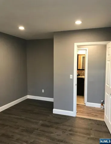 a view of an empty room with wooden floor and closet