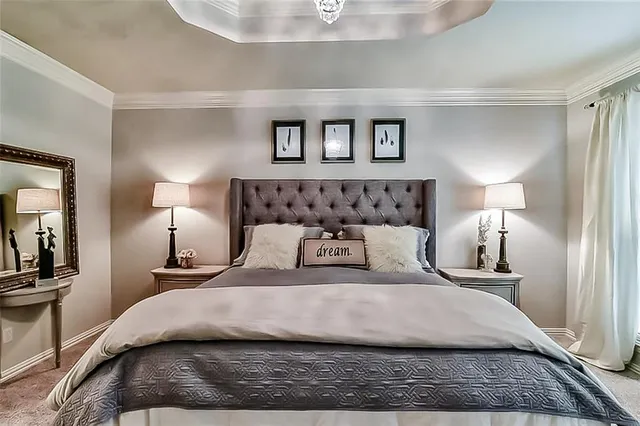 a bedroom with a large bed and a lamp on dresser