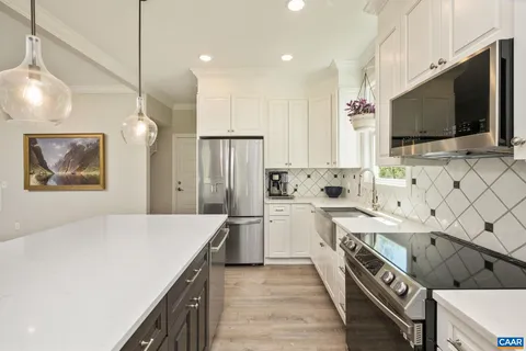 a kitchen with a refrigerator a sink dishwasher a dining table and chairs with wooden floor