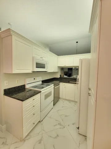 a kitchen with granite countertop white cabinets and white appliances