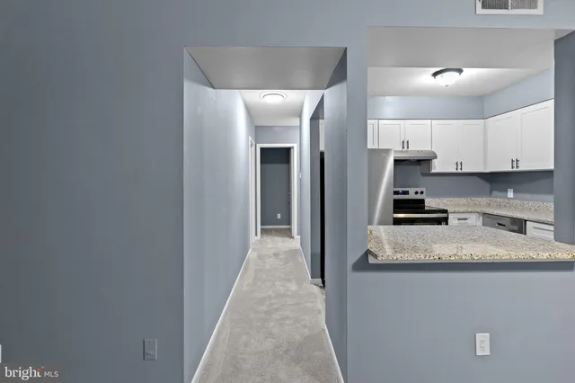 a view of a kitchen with granite countertop white cabinets and stainless steel appliances