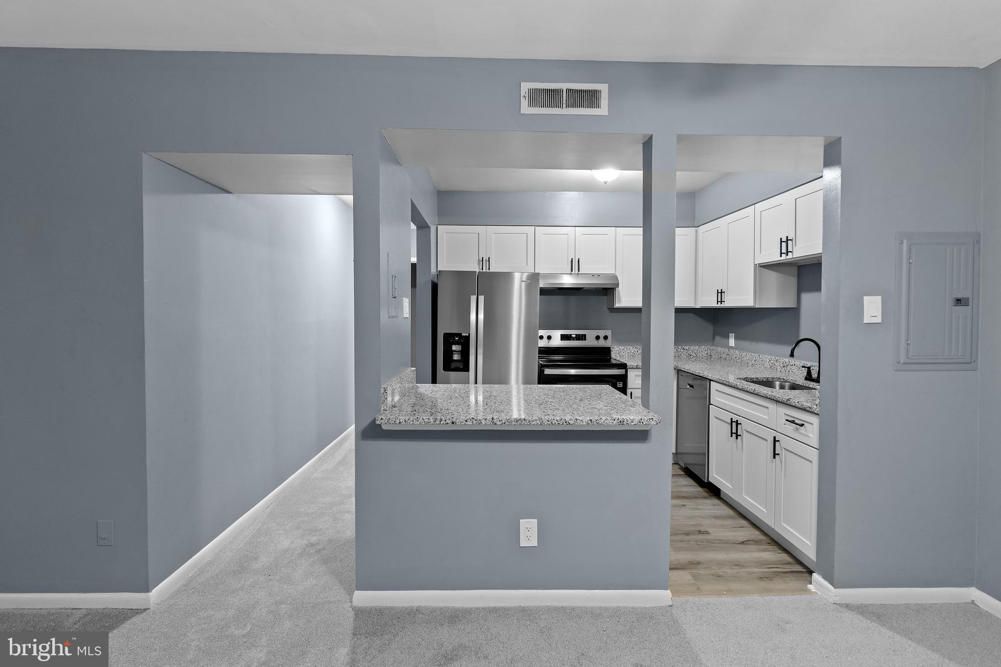 10121 Prince Place, Unit 30110B Upper Marlboro, MD 20774 - Photo 7 of 29 a large kitchen with stainless steel appliances kitchen island granite countertop a refrigerator a stove a sink and white cabinets with wooden floor