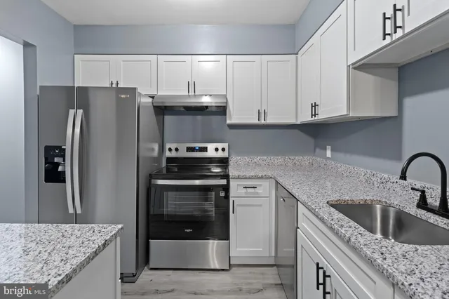 a kitchen with stainless steel appliances granite countertop a refrigerator sink and stove