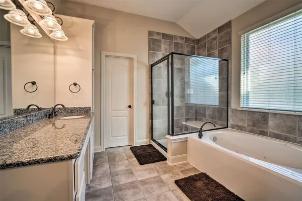 a bathroom with a granite countertop tub sink and mirror