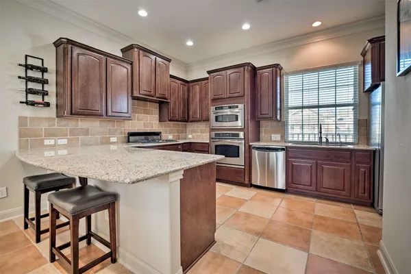 a kitchen with stainless steel appliances granite countertop a stove top oven a sink and a refrigerator