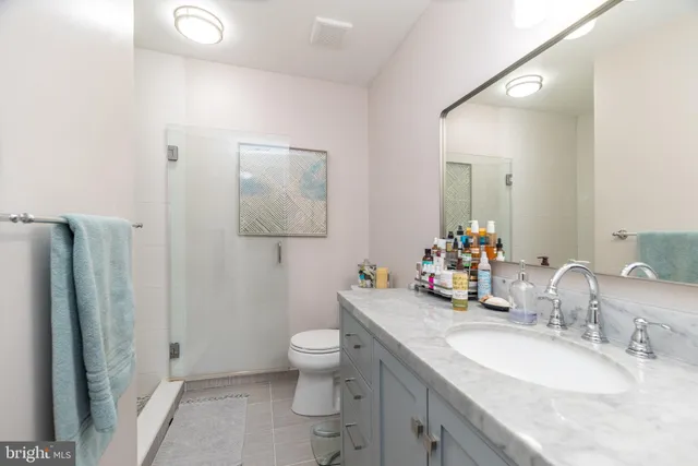 a bathroom with a granite countertop sink mirror vanity and toilet
