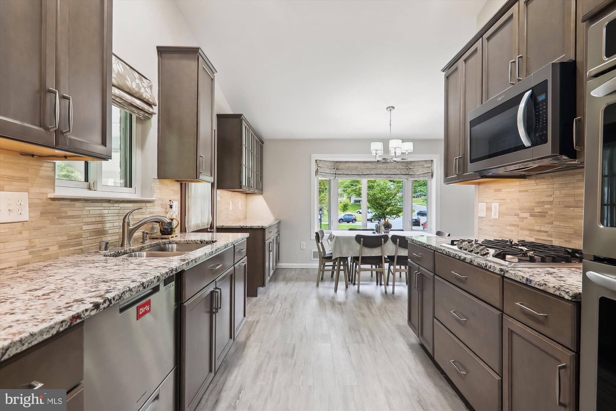 11804 Lovejoy Street Silver Spring, MD 20902 - Photo 14 of 45 a kitchen with stainless steel appliances granite countertop a stove top oven a sink dishwasher a dining table and chairs with wooden floor