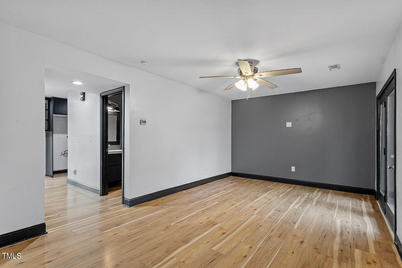 4274 Lake Ridge Drive Raleigh, NC 27604 - Photo 8 of 32 a view of an empty room with wooden floor and a ceiling fan