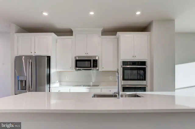 a kitchen with stainless steel appliances kitchen island granite countertop a refrigerator and a stove top oven