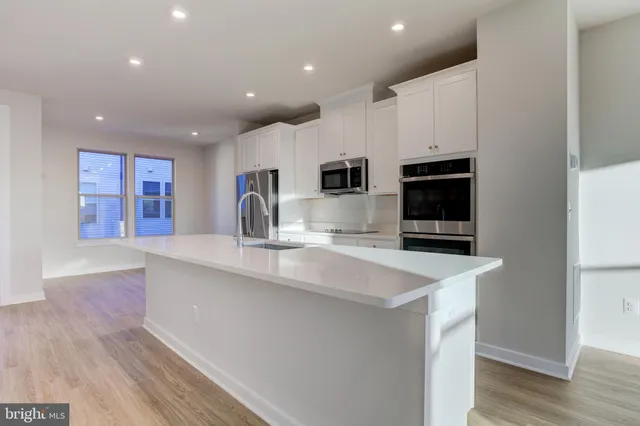 a large kitchen with stainless steel appliances a large counter top a stove and a refrigerator